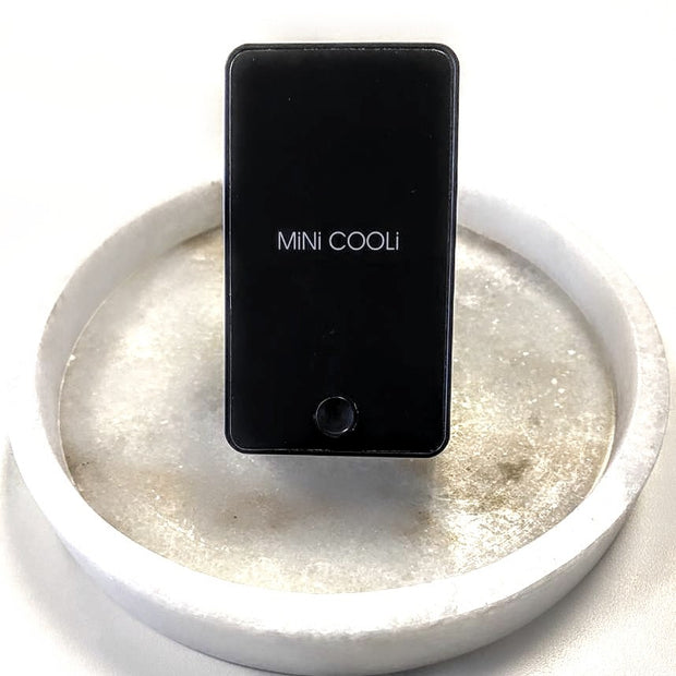 black mini cooli fan used for eyelash extensions on white background in a white ceramic dish